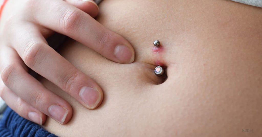 Woman touching her Belly button with piercing bump